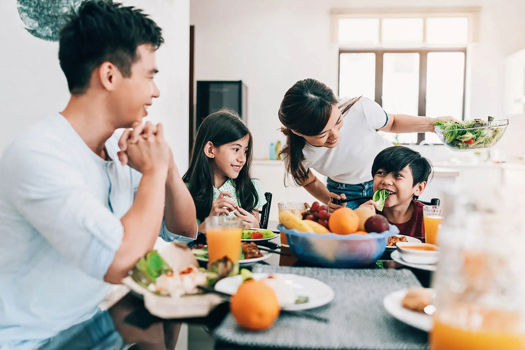 Family laughing while enjoying a meal in dining room